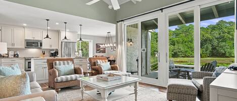 A spacious living area with a large glass door leading to a patio, a kitchen with modern appliances, and a ceiling fan.