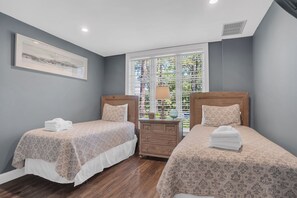 A hotel room with two beds, a nightstand, a lamp, and a window with blinds. - 1908 South Beach Club at The Sea Pines Resort (Hilton Head Island)