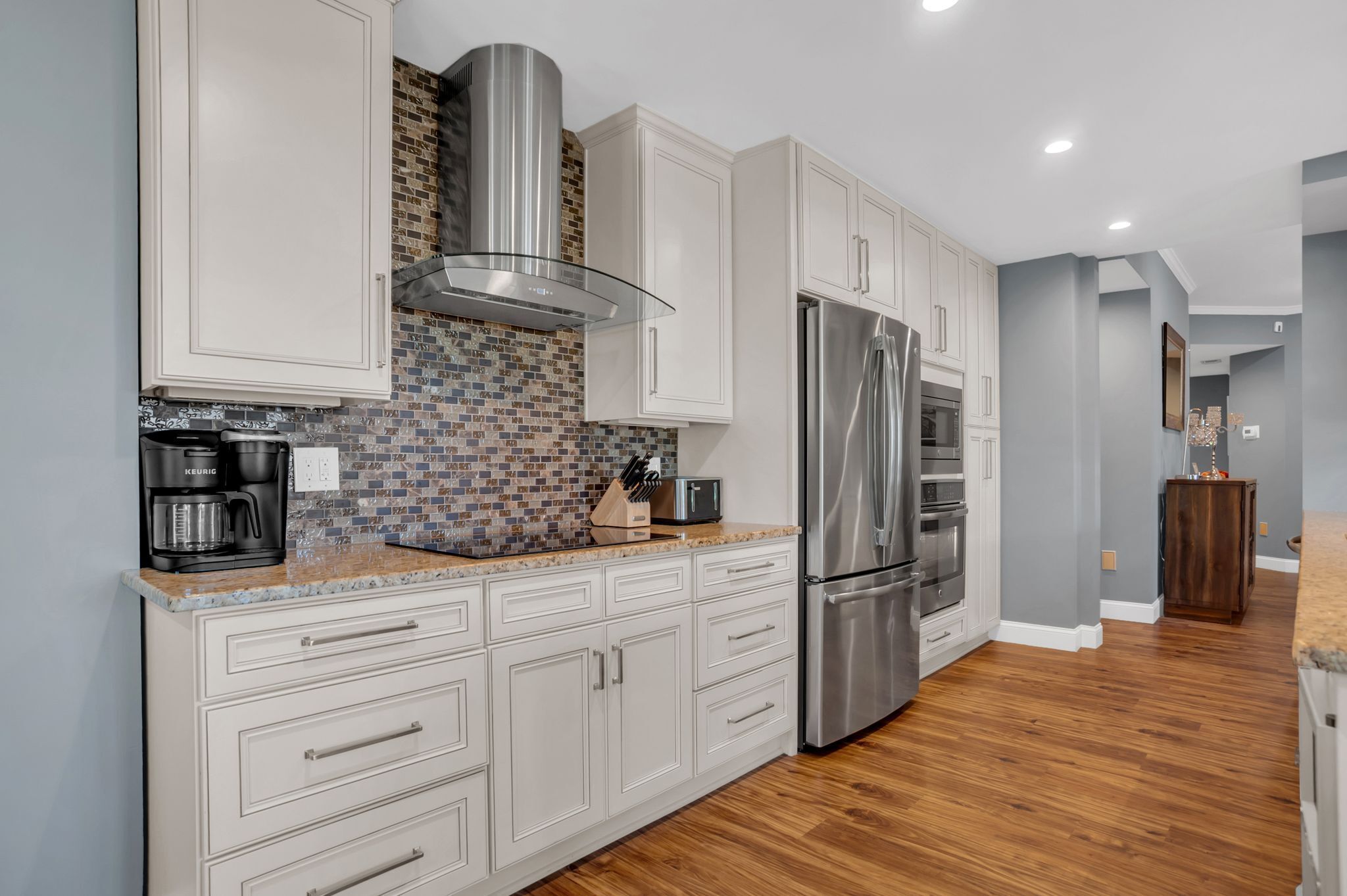 A modern kitchen with white cabinetry, a stainless steel refrigerator, and a tiled backsplash.