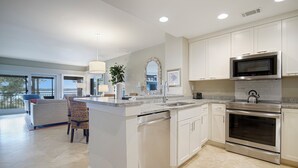 A modern kitchen with white cabinets, stainless steel appliances, and a large island. - 1857 Beachside Tennis at The Sea Pines Resort (Hilton Head Island)