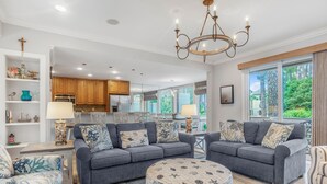 A spacious living room with a grey sofa set, a round ottoman with nautical prints, and a chandelier. - 1261 Harbour Town Club at The Sea Pines Resort (Hilton Head Island)
