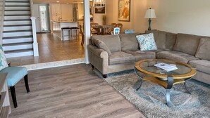 A spacious living area with a sofa, coffee table, and a view into the kitchen. - 1617 Port Villas at The Sea Pines Resort (Hilton Head Island)