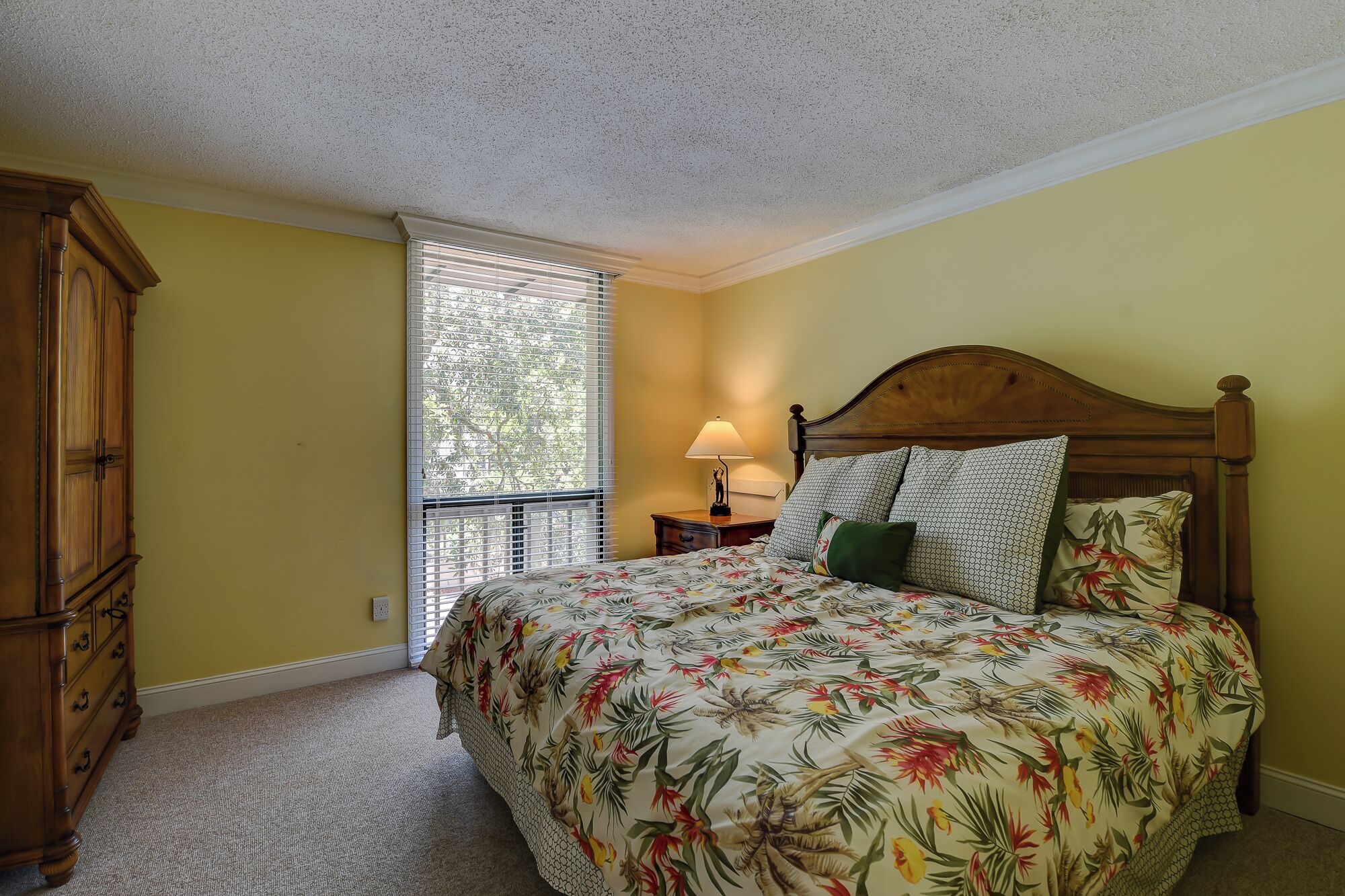 A bedroom with a bed, a nightstand, a lamp, and a wardrobe.