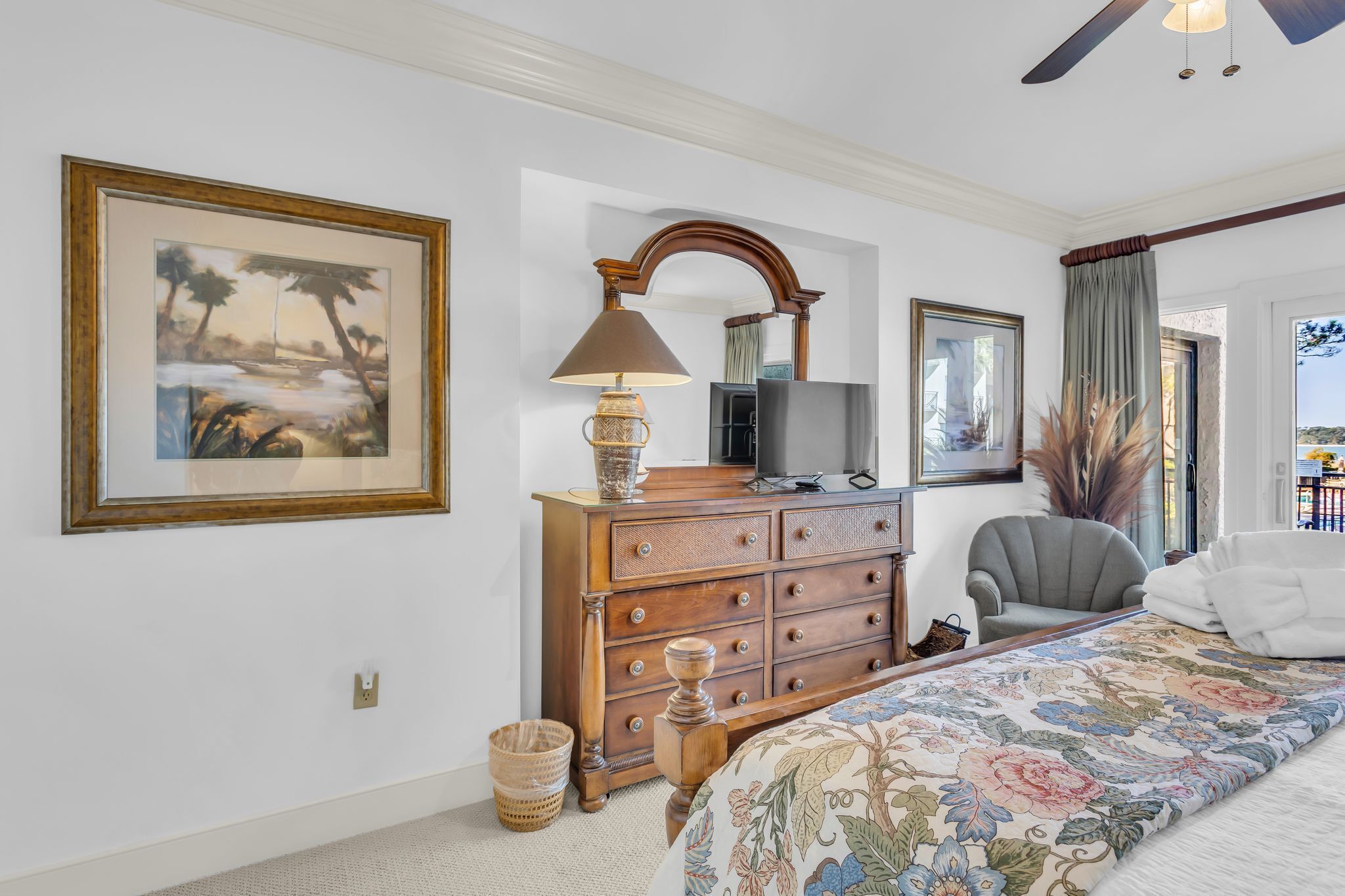 A bedroom with a bed, a dresser, a chair, a TV, and a framed picture on the wall.