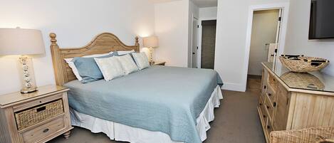 A bedroom with a bed, nightstands, a dresser, and a wicker chair.