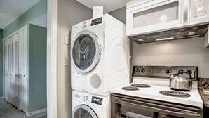 A laundry room with stacked front-loading washers and dryers, a microwave, and a stove. - 1739 Bluff Villas at The Sea Pines Resort (Hilton Head Island)