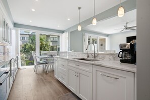 A kitchen with white cabinets, a marble countertop, a sink, and a coffee maker.