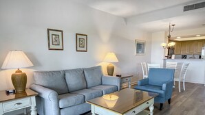 A living room with a grey sofa, a blue armchair, a wooden coffee table, and two lamps.