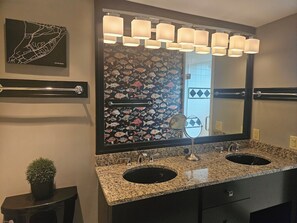 Une salle de bain avec deux lavabos, un grand miroir et des luminaires fixés au mur.