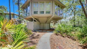 A unique house with a slanted roof and large windows, surrounded by a garden with various plants. - 2070 Deer Island at The Sea Pines Resort (Hilton Head Island)