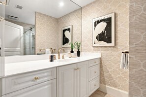A modern bathroom with a large mirror, two sinks, and decorative wall art. - 2001 Turtle Lane at The Sea Pines Resort (Hilton Head Island)