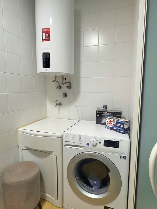 A compact laundry area with a washing machine, a dryer, and a small stool. - Family-friendly apartment with swimming pool and stunning views! (Madeira)