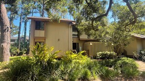 A two-story building with a beige exterior, surrounded by lush greenery and trees. - 1405 South Beach Villas at The Sea Pines Resort (Hilton Head Island)