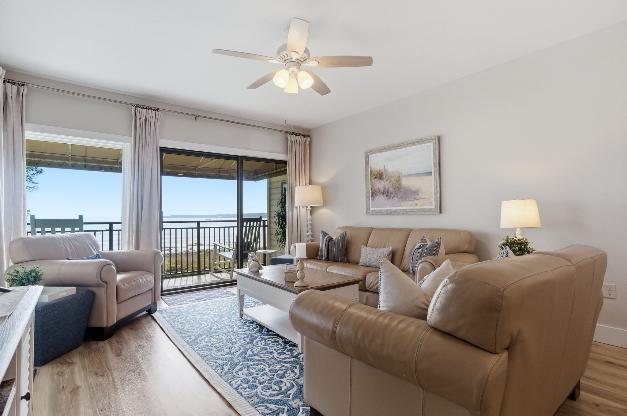 A spacious living room with a large window, a ceiling fan, and a view of the outdoors.