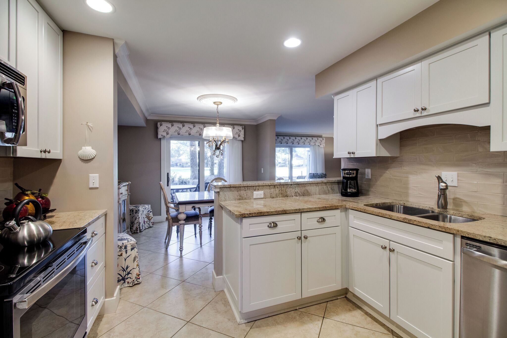 A modern kitchen with white cabinets, a granite countertop, and stainless steel appliances.