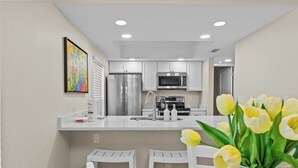 A modern kitchen with white cabinets, stainless steel appliances, and a central island. - Gulf-Front 3BR Sanibel Condo with Stunning Views! (Sanibel)