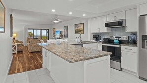 Una cocina moderna con gabinetes blancos, encimeras de granito y electrodomésticos de acero inoxidable.
