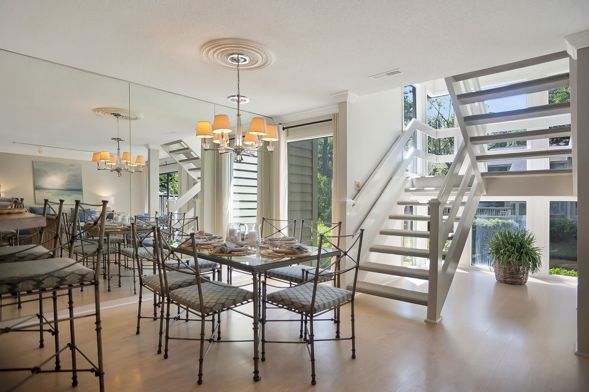 Un'ampia sala da pranzo con soffitto alto, lampadario moderno e una scala che conduce a un piano superiore.