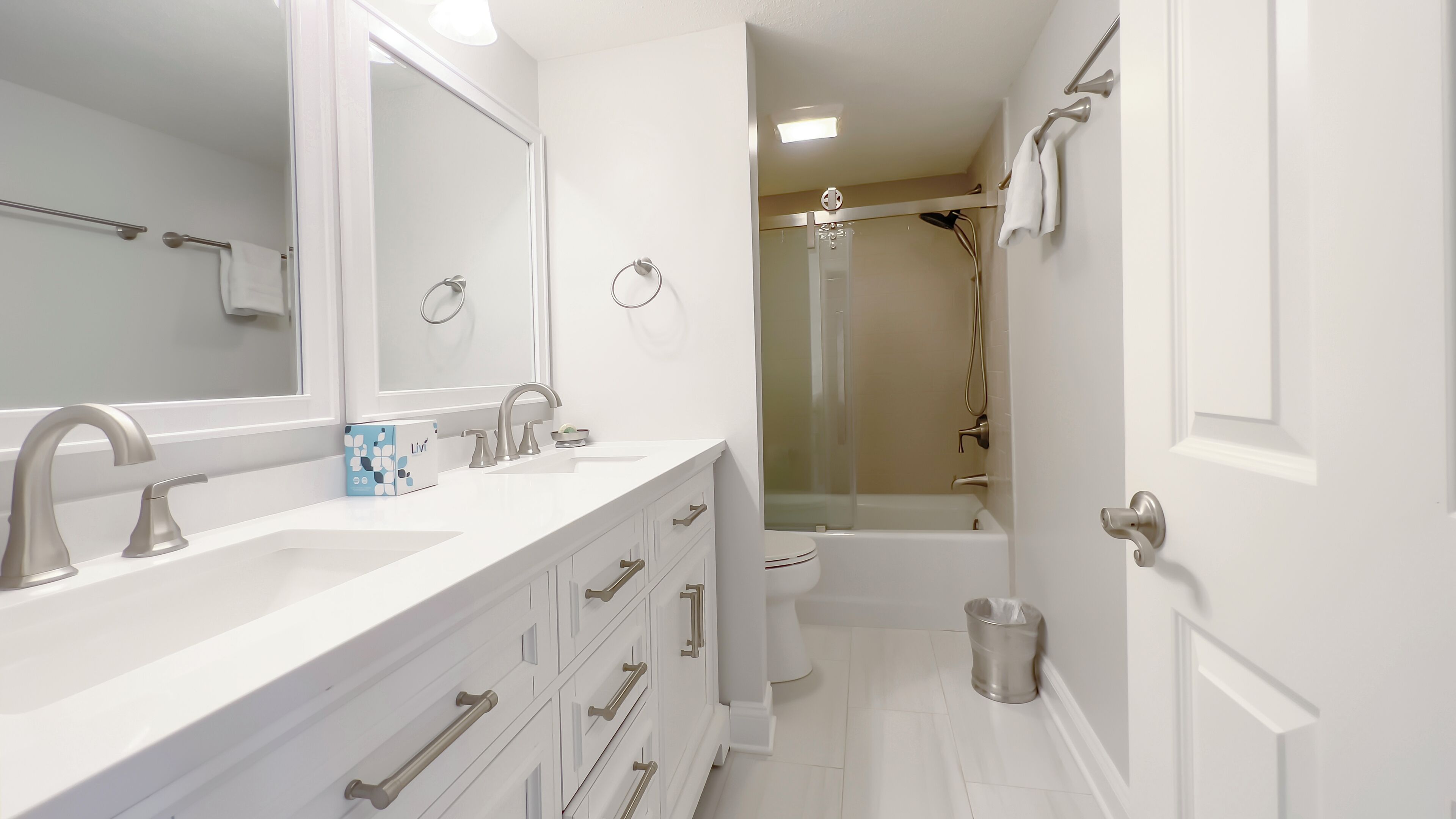 Un bagno moderno con un mobile lavabo bianco, uno specchio grande, una doccia e un water.