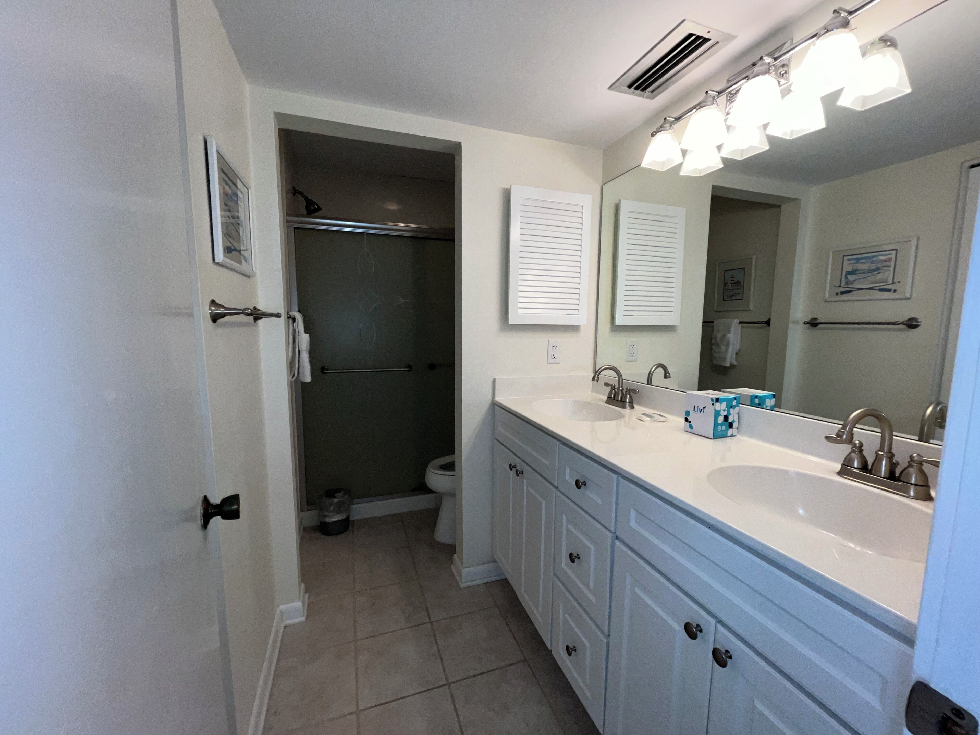 A bathroom with a white sink, a mirror, and a shower area.
