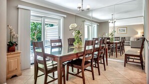 A dining area with a glass table and wooden chairs, a chandelier, and a view of the outdoors through large windows. - 2279 Heritage Villas at The Sea Pines Resort (Hilton Head Island)