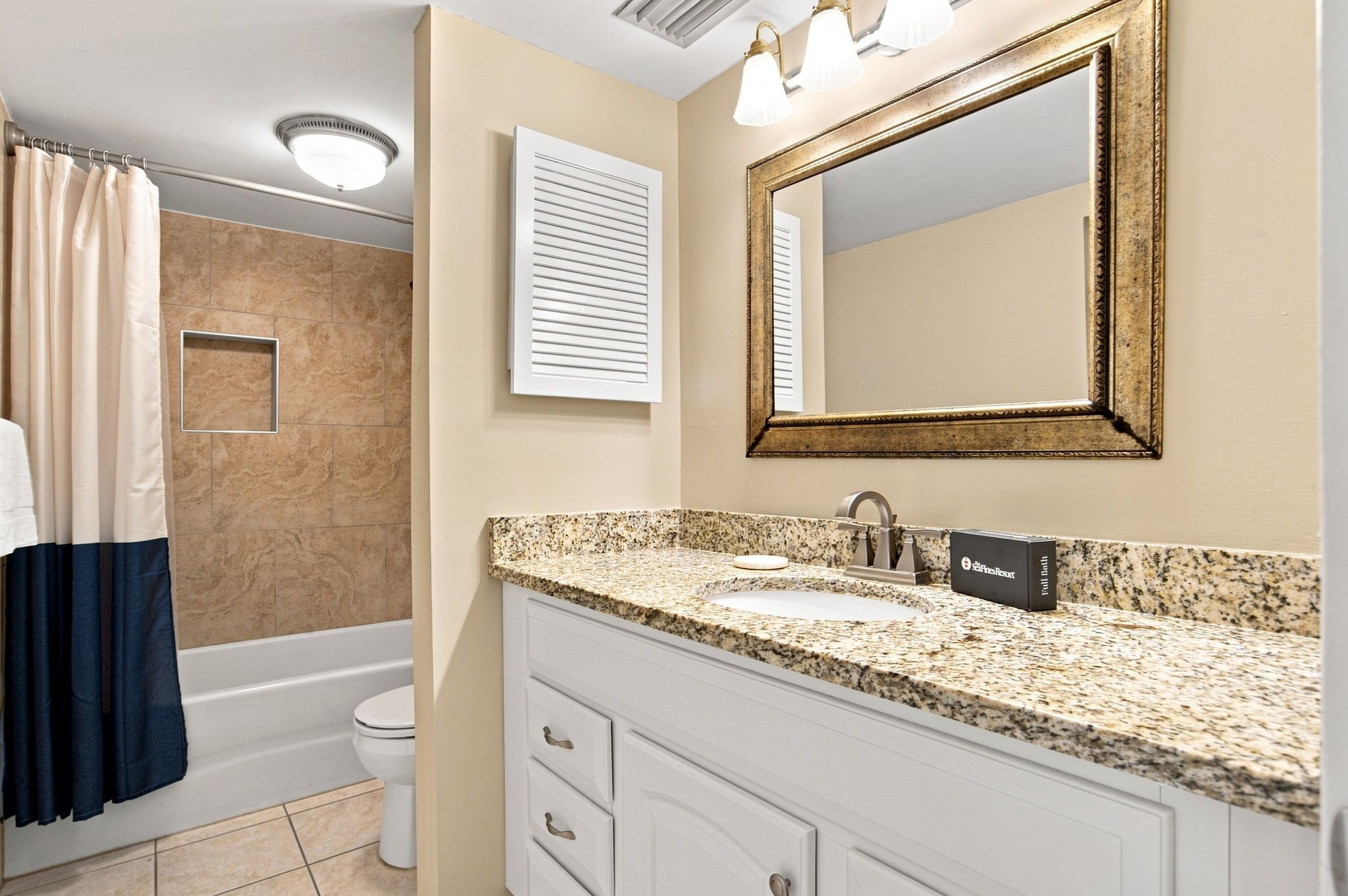 A bathroom with a sink, mirror, and shower area.