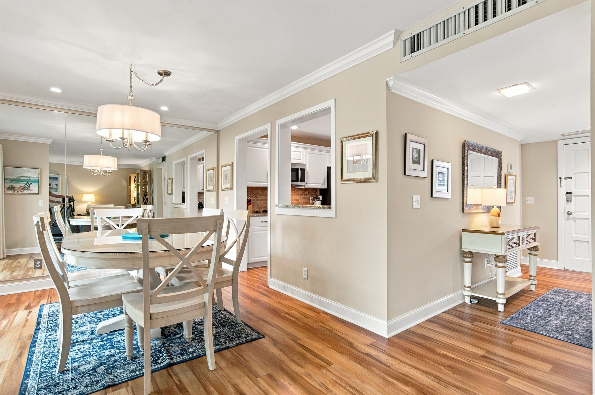 A spacious living area with a dining table, chairs, and a kitchen in the background.