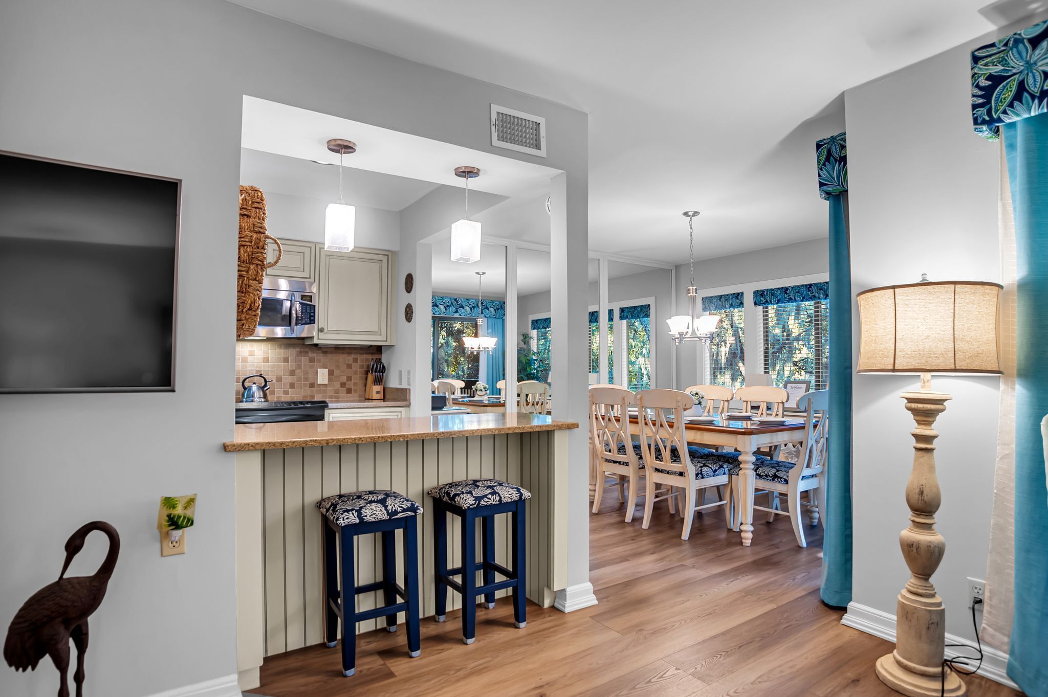 Une cuisine moderne dotée d’un îlot central, de tabourets de bar en bois et d’un coin repas avec une table et des chaises.