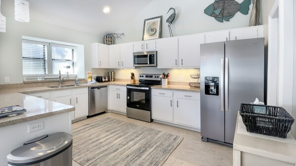 A modern kitchen with white cabinets, stainless steel appliances, and a granite countertop. - 2622 Calibogue Club at The Sea Pines Resort (Hilton Head Island)