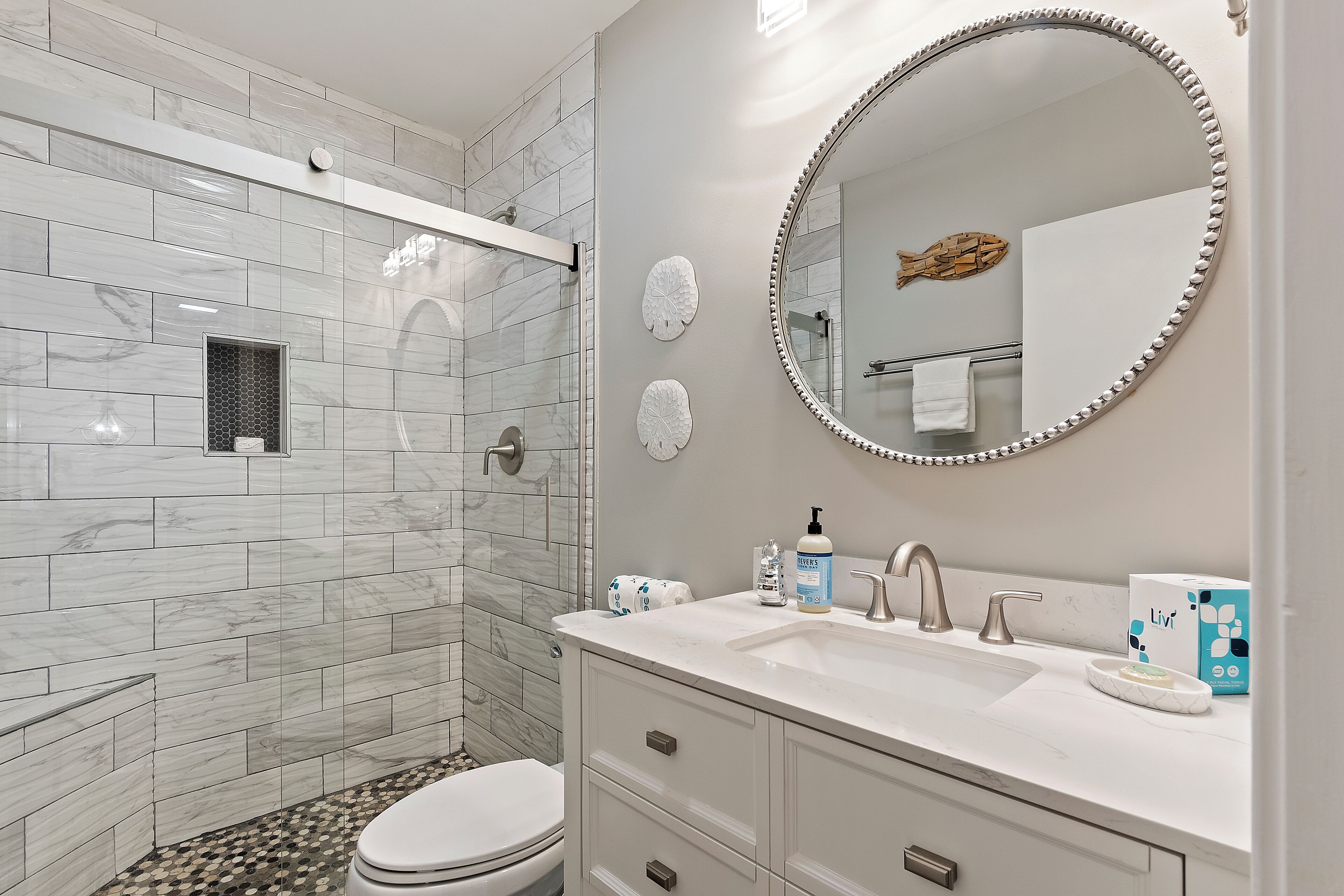 Un baño con ducha, inodoro y tocador con lavabo y espejo.