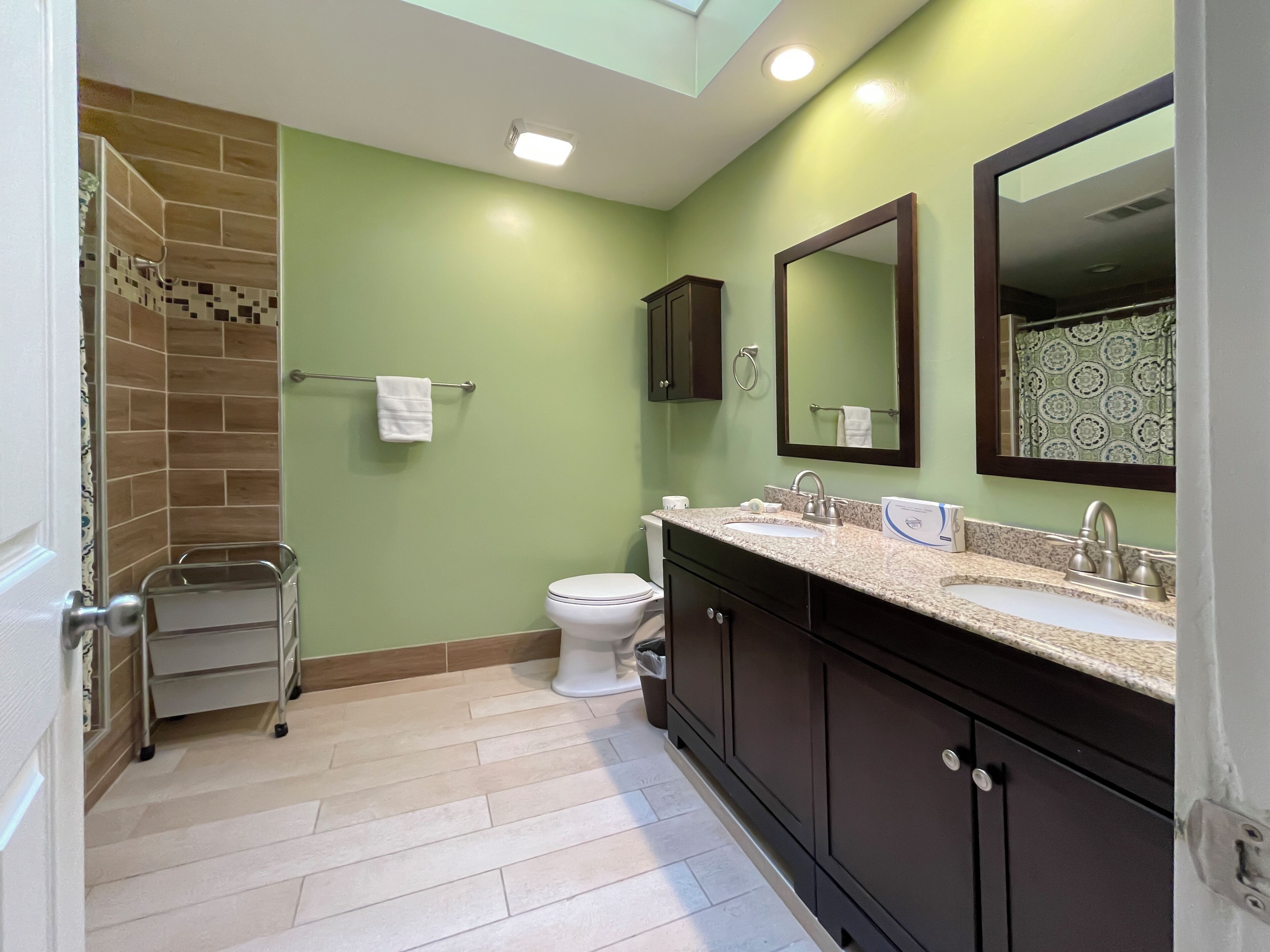 A bathroom with a shower, toilet, sink, and vanity.