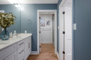 A modern bathroom with a white vanity, a large mirror, and a vase with flowers. - 6966 Fairway One at The Sea Pines Resort (Hilton Head Island)