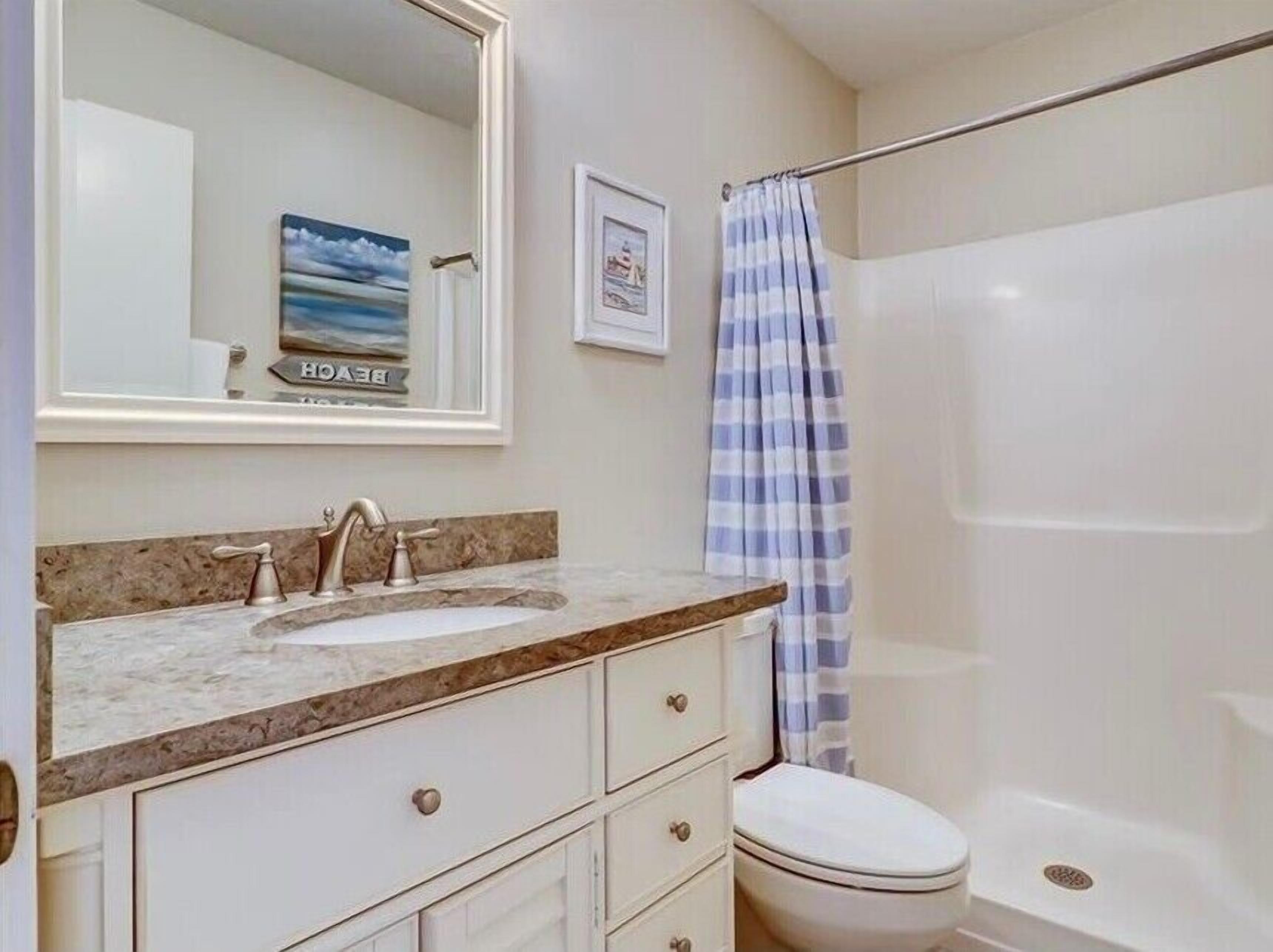 A bathroom with a sink, mirror, and a shower curtain.