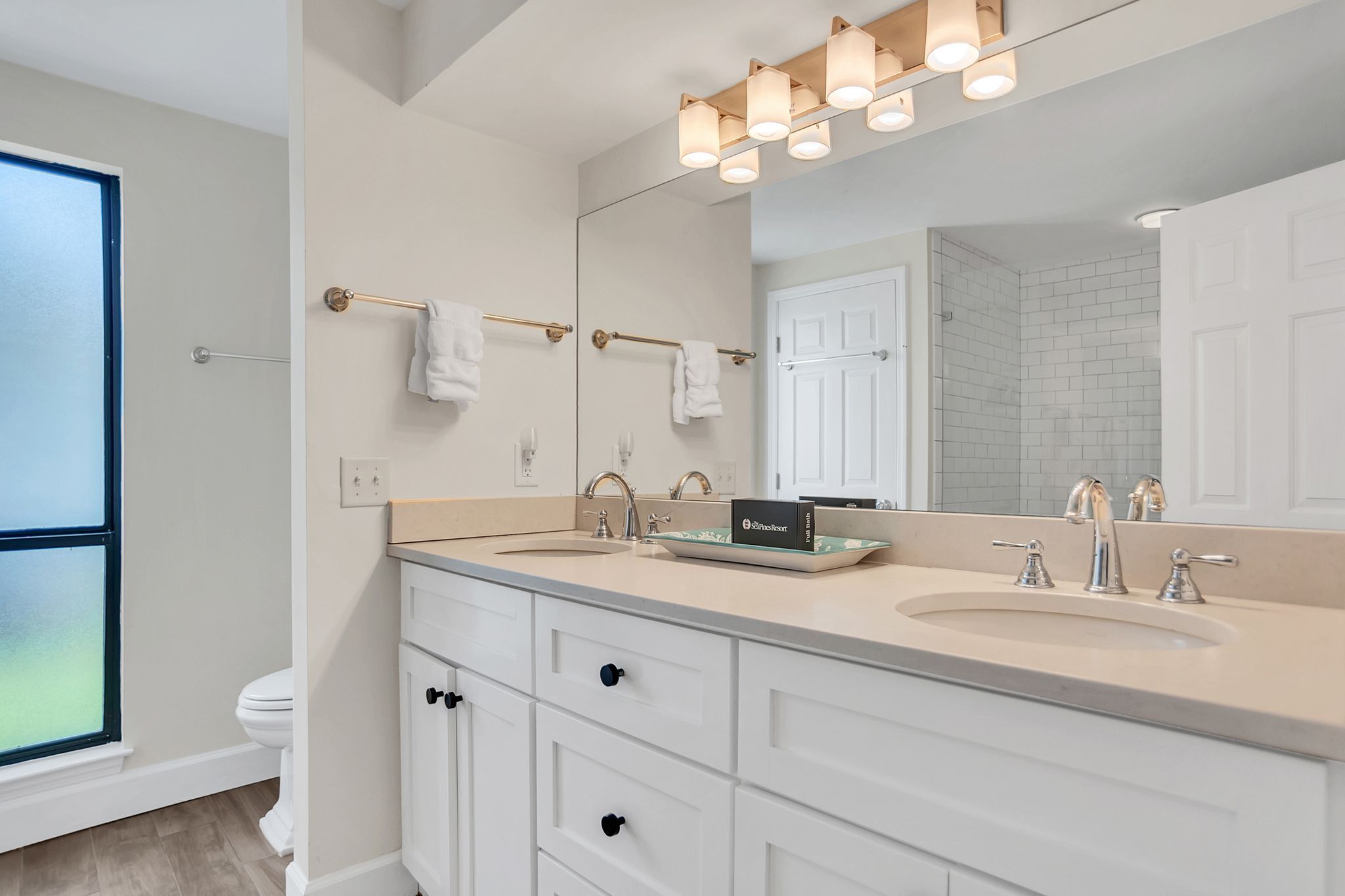 A modern bathroom with two sinks, a large mirror, and a towel rack.