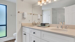 A modern bathroom with two sinks, a large mirror, and a towel rack. - 2629 Calibogue Club at The Sea Pines Resort (Hilton Head Island)
