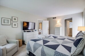 Ein Schlafzimmer mit Bett, Fernseher, Kommode, Stuhl und Lampe.