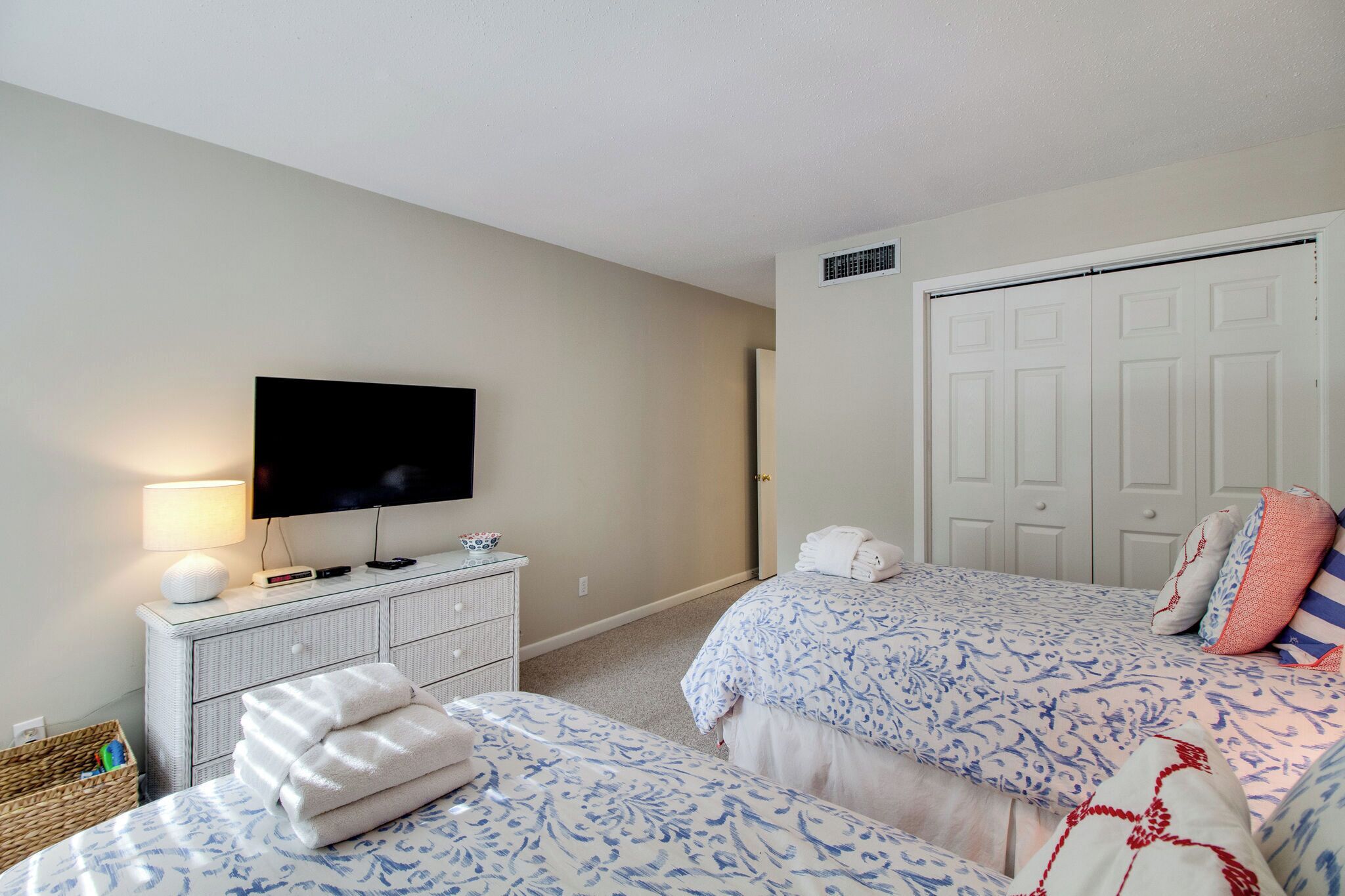 A bedroom with two beds, a television, a dresser, and a closet.