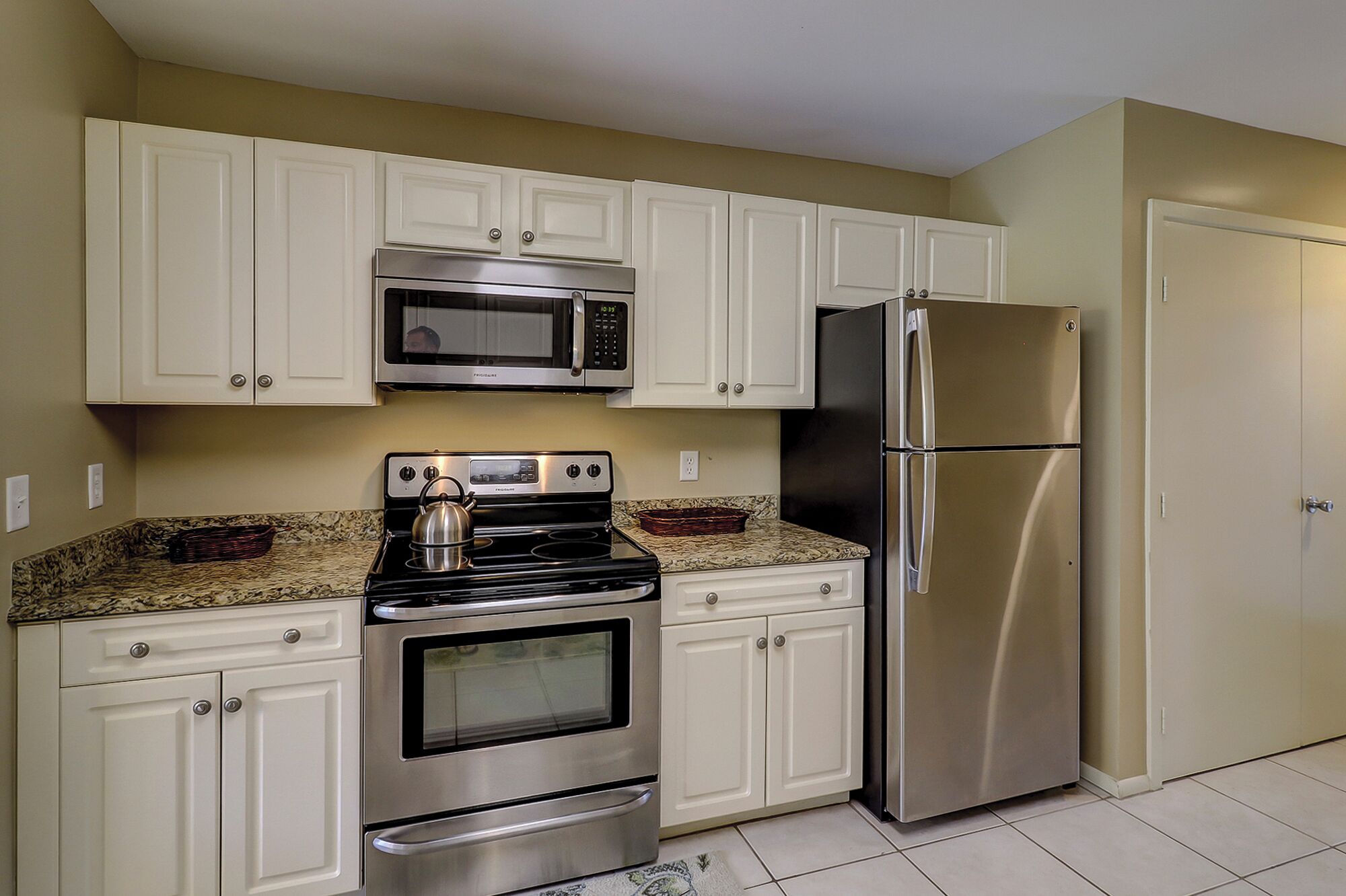 A kitchen with white cabinets, stainless steel appliances including a stove, oven, microwave, and refrigerator.