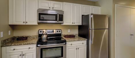 A kitchen with white cabinets, stainless steel appliances including a stove, oven, microwave, and refrigerator.