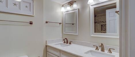 A bathroom with two sinks, a toilet, and a mirror.