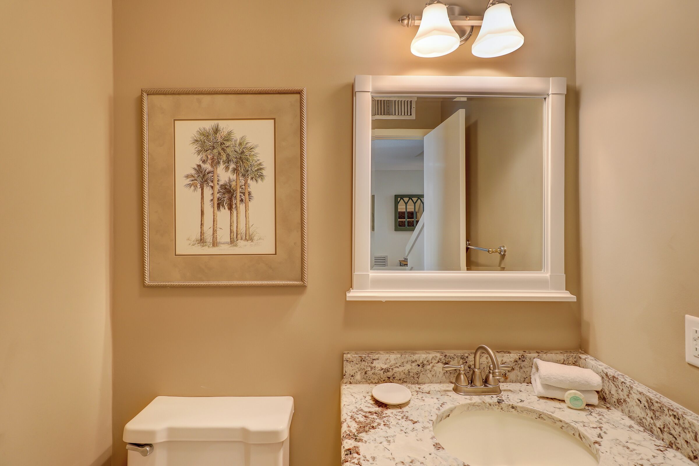 A bathroom with a toilet, sink, and framed artwork.