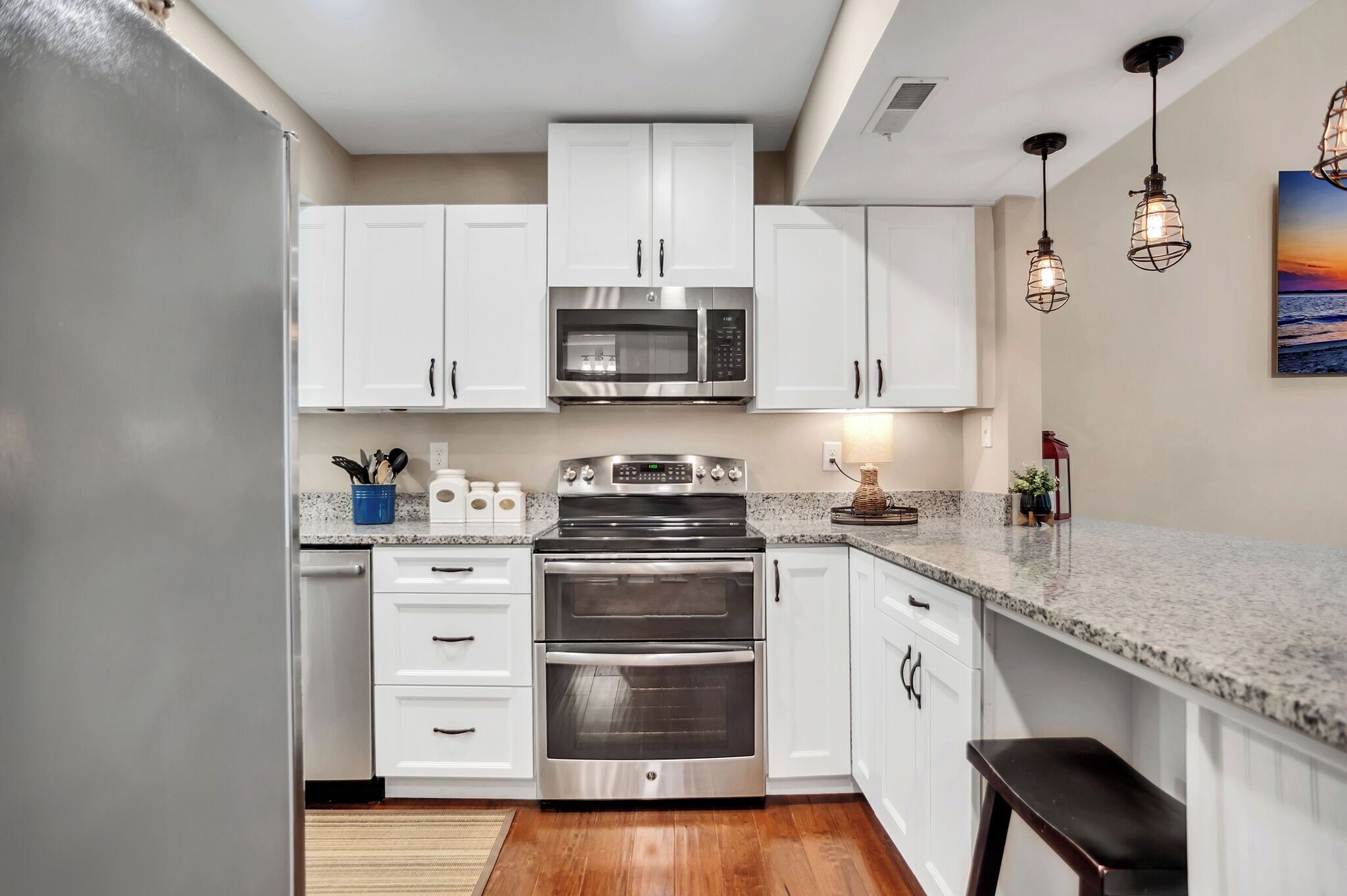 A kitchen with white cabinets, stainless steel appliances, and a granite countertop.