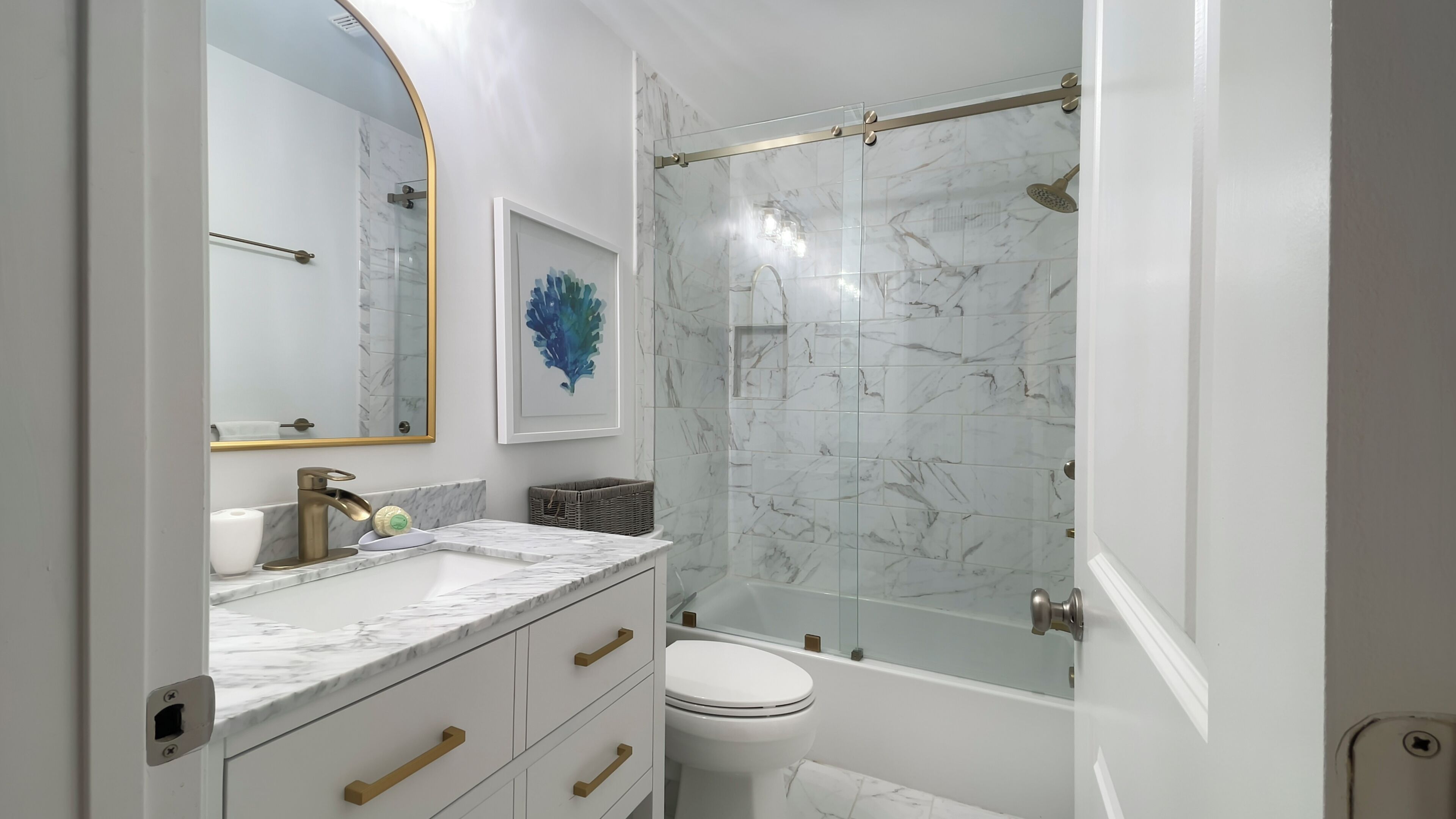 Un baño moderno con tocador de mármol, cabina de ducha de vidrio y inodoro blanco.