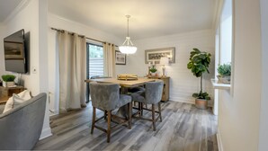 A dining area with a wooden table, two bar stools, a chandelier, and a potted plant. - 2309 Heritage Villas at The Sea Pines Resort (Hilton Head Island)