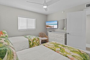Een slaapkamer met twee bedden, een televisie, een dressoir, een stoel en een deur.