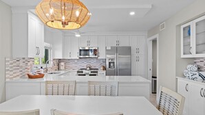 A modern kitchen with white cabinets, stainless steel appliances, and a central island with seating. - Gulf-View Escape | Bright & Breezy 2BR Condo Steps from the Beach (Sanibel)