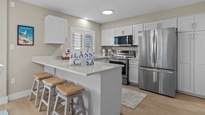 Una cocina moderna con armarios blancos, electrodomésticos de acero inoxidable y una isla central con taburetes.