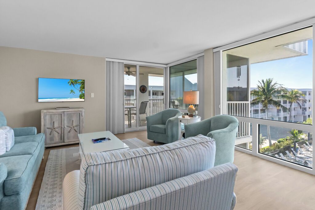 A modern living room with a large balcony, a television, and a view of the ocean.