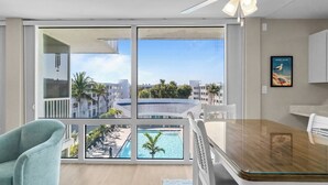 Una habitación moderna con un amplio ventanal con vistas a una piscina y edificios.