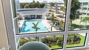 Vista de una piscina con sillas de descanso y un edificio al fondo.